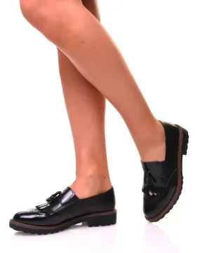 Black two-material moccasins with fringes and a pompom.
